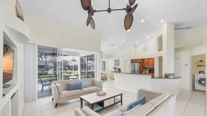 A spacious living area with a sofa set, a coffee table, and a kitchen in the background. - Seaside Waterfront Home | Heated Pool & Dock (Marco Island)
