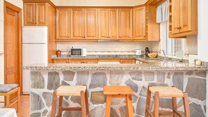 Una cocina con armarios de madera, una isla de piedra y dos taburetes.