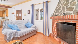 Una sala de estar acogedora con un sofá, una chimenea y una cocina al fondo.