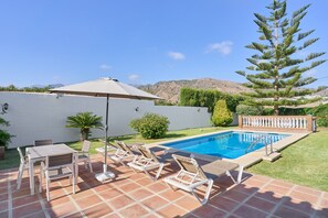 A swimming pool with a tiled deck, lounge chairs, a table, and an umbrella. - Villa 'El Peli' with Sea View, Wi-Fi and Air Conditioning (Nerja)