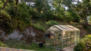 A greenhouse with a glass roof, surrounded by greenery and a concrete wall. - "Azur" Room with Shared Pool, Wi-Fi, and Air Conditioning (Collobrières)
