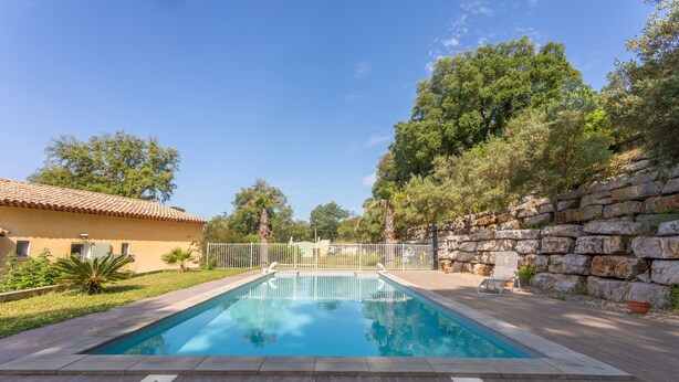 Une piscine rectangulaire avec un mur en pierre et une structure de toit en carrelage en arrière-plan.
