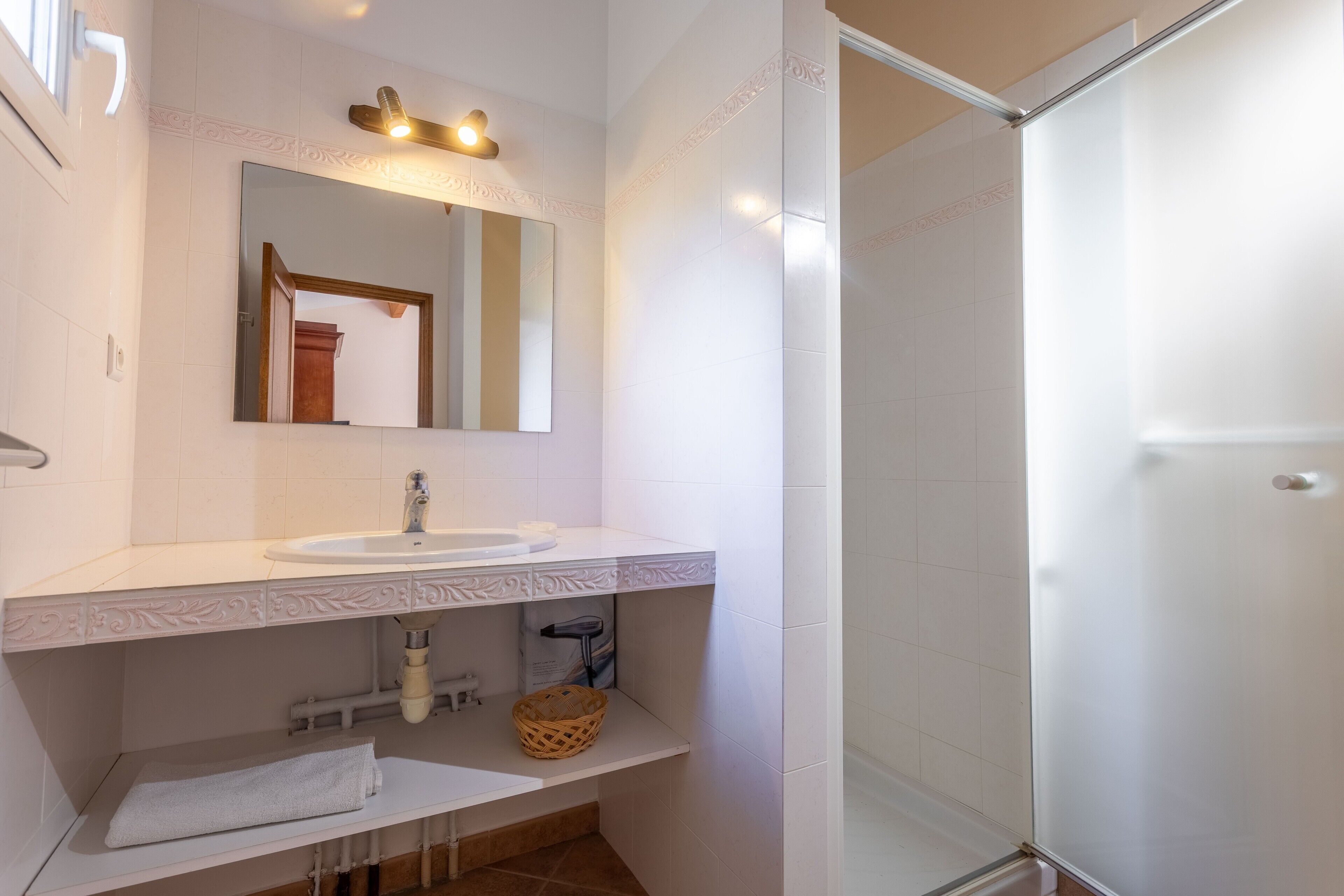 A bathroom with a white sink, mirror, and shower.