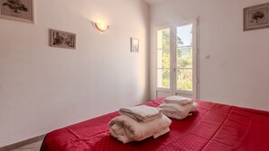 Une pièce avec un lit, une fenêtre et des tableaux accrochés au mur.