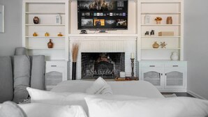 Ein Schlafzimmer mit Kamin, einem darüber montierten Fernseher und integrierten Regalen an beiden Seiten.