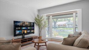 Ein Wohnzimmer mit Flachbildfernseher, einem runden Couchtisch und zwei beigefarbenen Sofas.