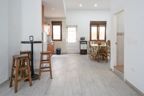 Una cocina con taburetes de madera, una mesa de comedor con sillas, un microondas y un refrigerador.