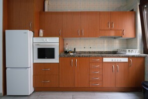 Una cocina con armarios de madera, un refrigerador blanco, un horno y un lavavajillas.