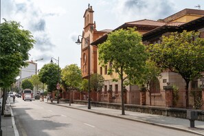 Eine Straße mit einem Gebäude, das einen Glockenturm und einen roten Zaun hat.