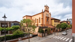 A street view with a church, a crosswalk, and a parked car. - Holiday Home 'Little Yellow House' with Private Terrace (Gijón)