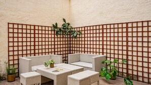A corner seating area with wicker furniture, a small table, and potted plants. - Holiday Home 'Little Yellow House' with Private Terrace (Gijón)