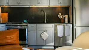 A compact kitchen with grey cabinets, a stainless steel refrigerator, and a small countertop.