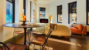 A modern living room with a round table, wireframe chairs, a sofa, and a TV displaying the Netflix logo.