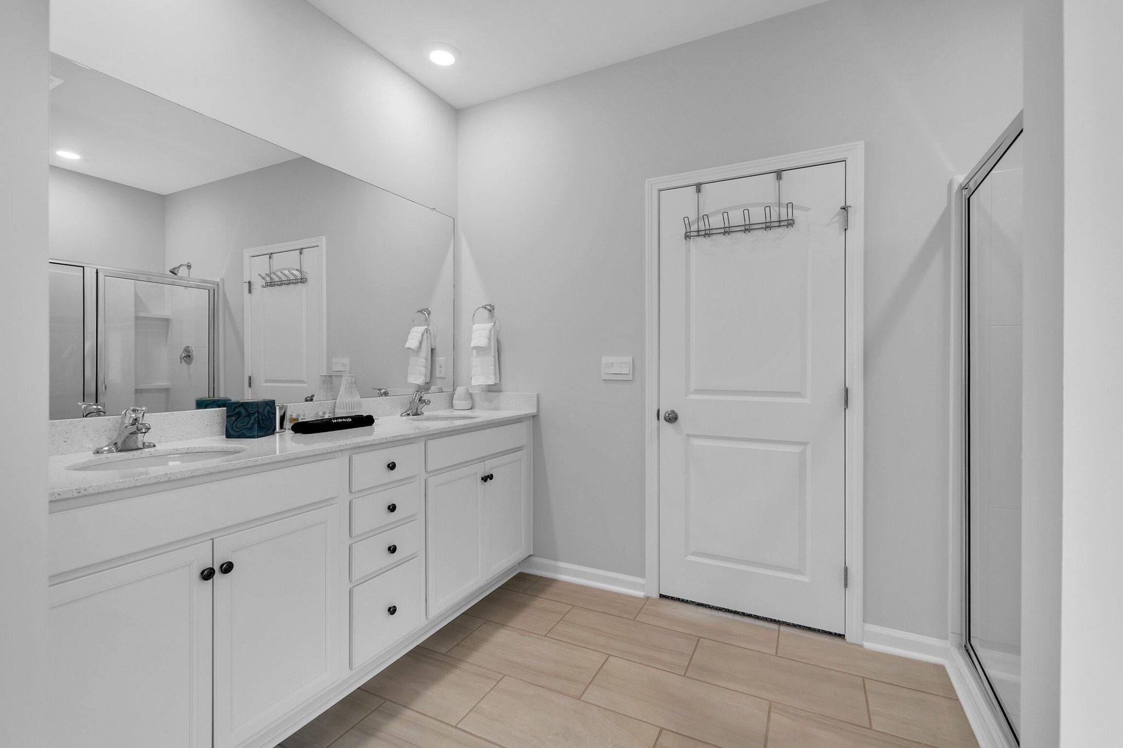 A modern bathroom with a white vanity, a large mirror, and a shower area.