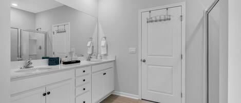 A modern bathroom with a white vanity, a large mirror, and a shower area.