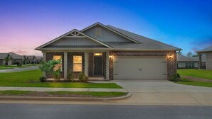 Una casa a un piano con garage, un portico e un prato curato.