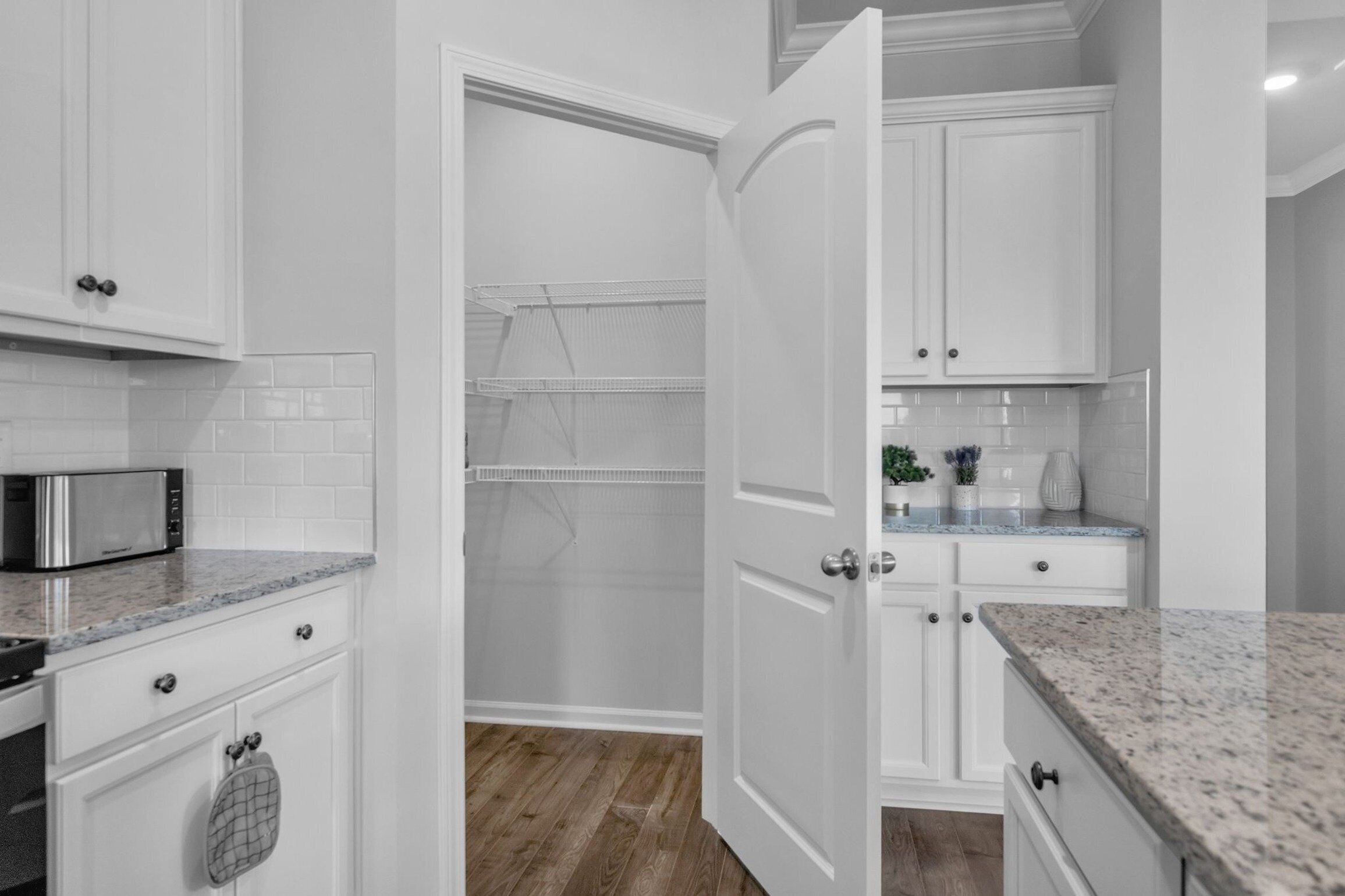 A modern kitchen with white cabinetry, a microwave, and a countertop.