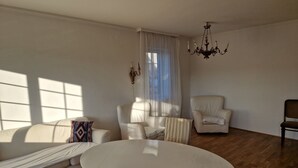 Un salon spacieux avec une grande table ronde, un canapé et deux fauteuils.