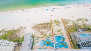 An aerial view of a beach with a swimming pool and beach umbrellas. - Phoenix Gulf Shores Ii 2304 3 Bedroom Condo (Gulf Shores)