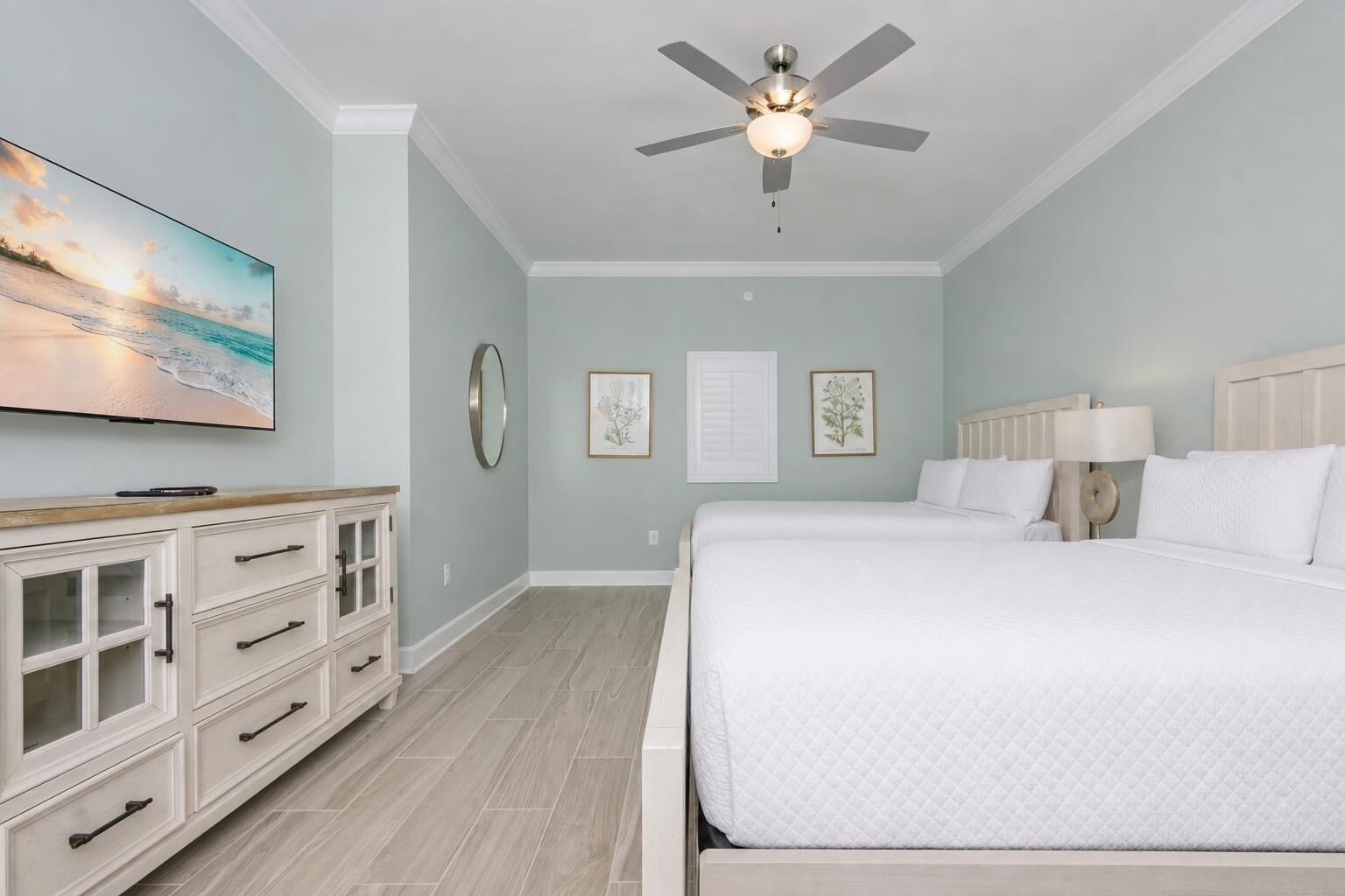 A bedroom with a bed, a ceiling fan, a dresser, and a painting on the wall.