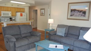 A living room with two grey sofas, a blue coffee table, and a small side table with a lamp. - 2909 2 Bedroom Villa (Calabash)