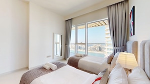 Ein Hotelzimmer mit zwei Betten, einem großen Fenster und Stadtblick sowie einer modernen Lampe.