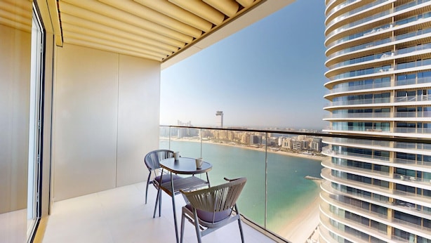 Ein Balkon mit Blick auf eine Küstenstadt, ausgestattet mit einem Tisch und zwei Stühlen.