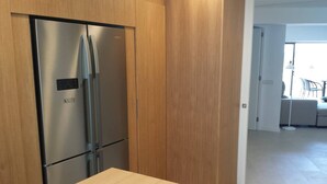 A kitchen with a stainless steel refrigerator, wooden cabinets, a light-colored countertop, and a basket of lemons. - Apartment 'Maina' with Sea View, Wi-Fi and Air Conditioning (Pollença)
