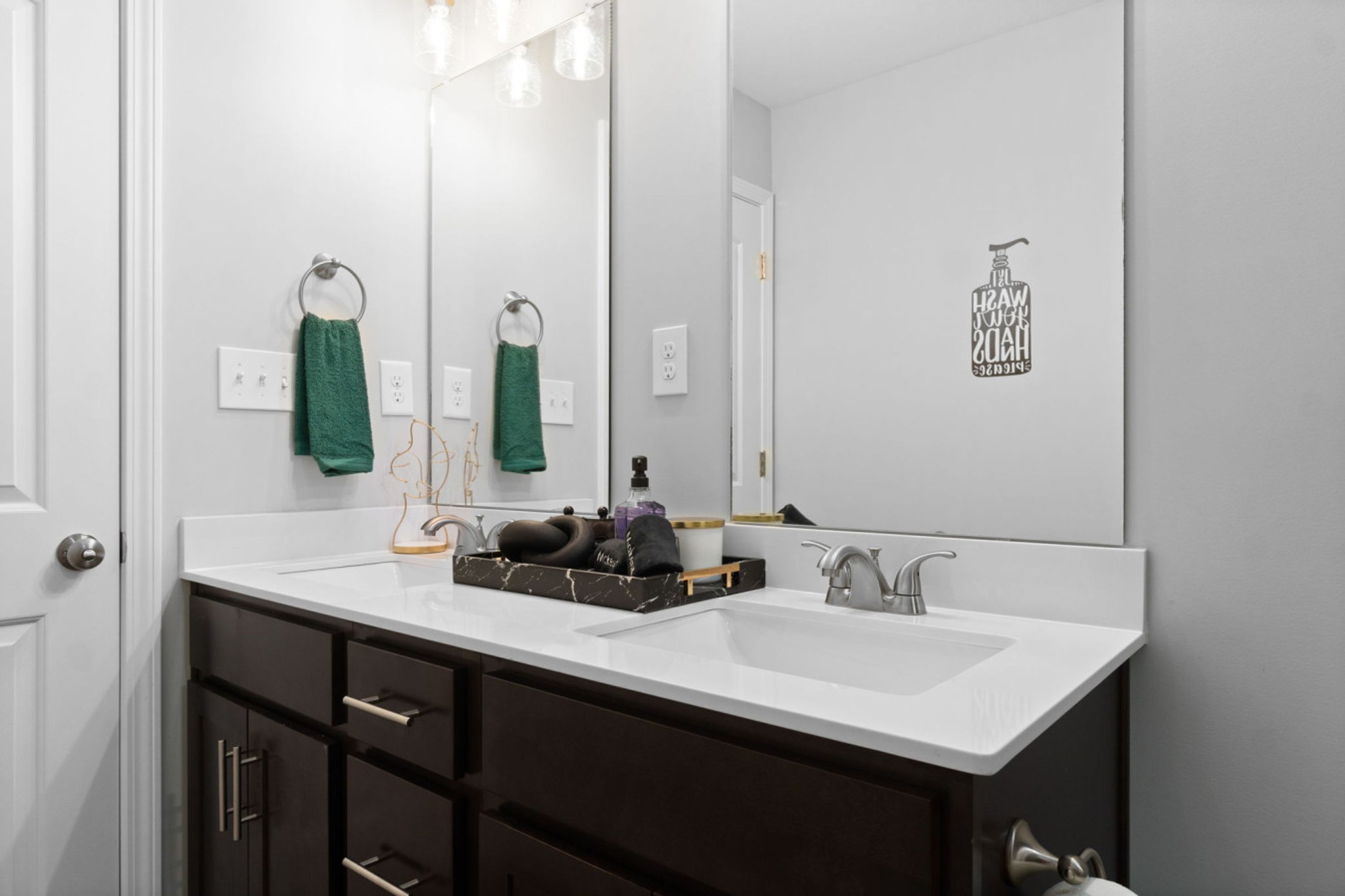 A modern bathroom with a white vanity, dark cabinets, and a large mirror.