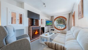 Una sala de estar moderna con chimenea, televisor y un amplio ventanal con vistas.