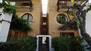 Un edificio con entrada central, dos balcones y un árbol en primer plano.