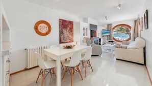 Una sala de estar moderna con comedor, un sofá, un televisor y vista al mar.
