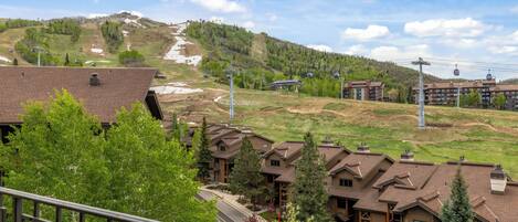 A mountain resort with multiple buildings, a ski slope, and a clear sky.