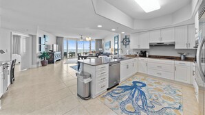 A modern kitchen with white cabinets, a stainless steel dishwasher, and a large island.