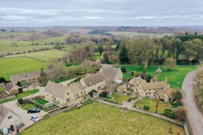 A rural village with traditional stone houses, a central courtyard, and surrounding fields. - Country Cottage in the Heart of the Cotswolds (Cheltenham)