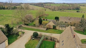A rural property with stone buildings, a fenced garden, and expansive fields. - Country Cottage in the Heart of the Cotswolds (Cheltenham)
