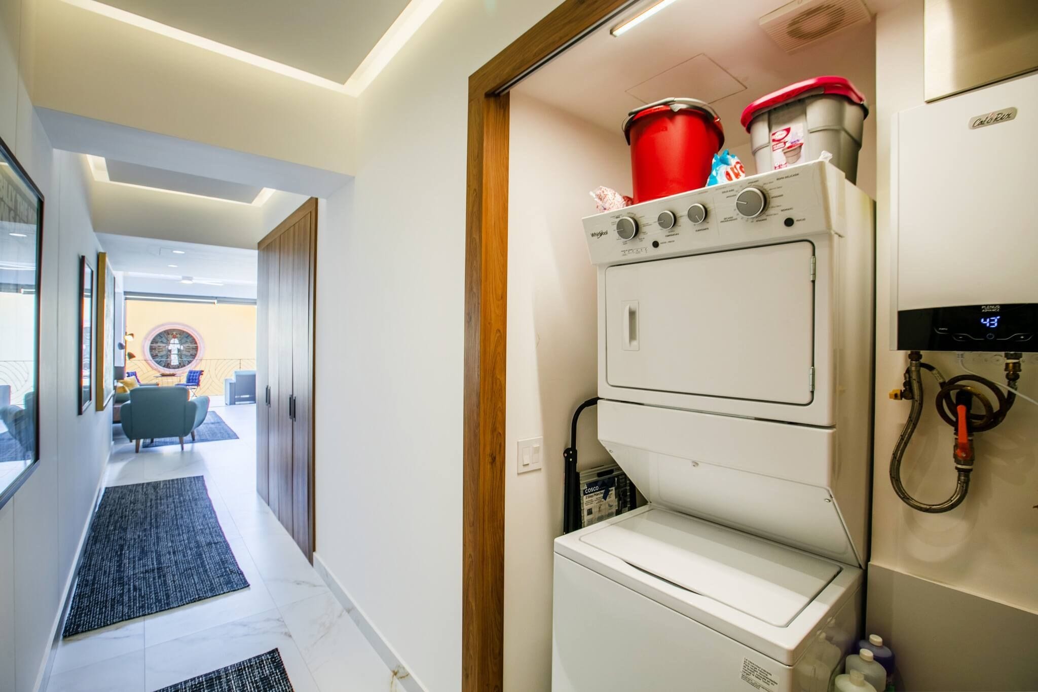Habitación de hotel con diseño moderno, que incluye lavadora y secadora integradas, una puerta de madera y vistas al exterior.