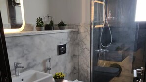 Un bagno moderno con lavabo in marmo, un water e zona doccia.