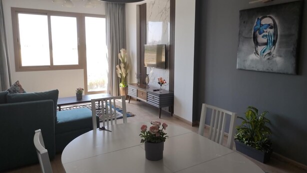 Un soggiorno moderno con zona pranzo, un divano, una TV e un quadro appeso al muro.