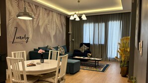 Un soggiorno moderno con zona pranzo, caratterizzato da un divano, un tavolino da caffè e un lampadario.