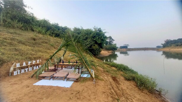 A birthday setup by a lakeside with a table, chairs, and a 'Happy Birthday' sign. - Bastar Birds Nest (Jagdalpur)