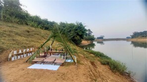 A birthday setup by a lakeside with a table, chairs, and a 'Happy Birthday' sign. - Bastar Birds Nest (Jagdalpur)
