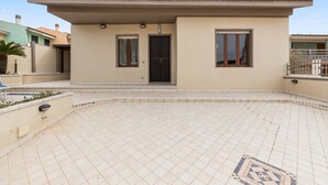 Un bâtiment doté d’une terrasse carrelée, d’une porte et de fenêtres.
