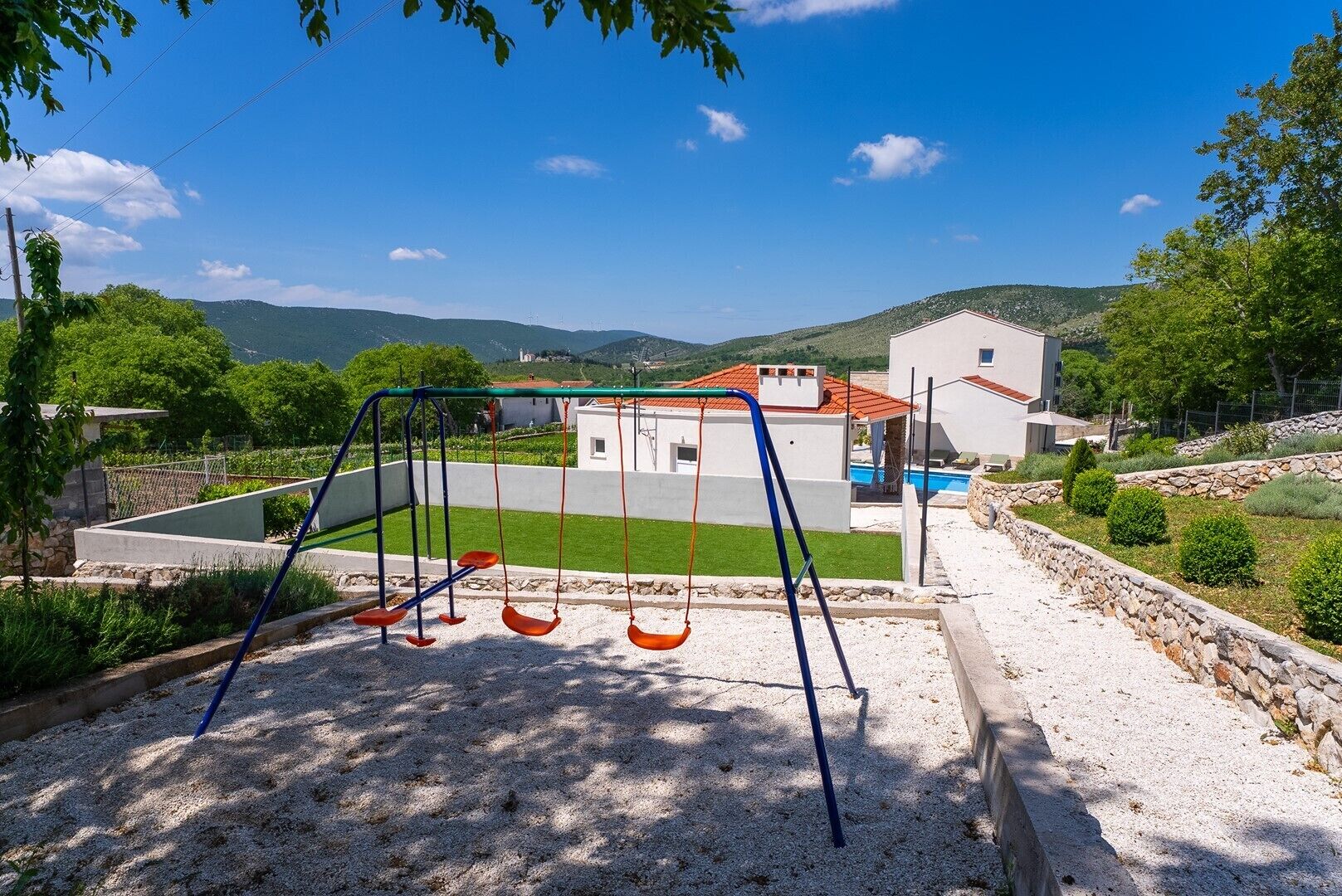 A playground with swings and a house in the background.