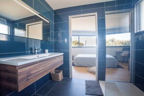 A modern bathroom with a wooden vanity, a large mirror, and a glass shower enclosure.
