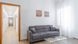 A modern living room with a grey sofa, a glass coffee table, and two artworks on the wall. - Apartment 'Libellula' with Balcony, Wi-Fi and Air Conditioning (Siracusa)