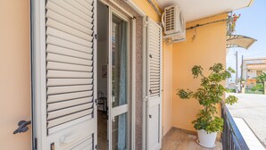 A balcony with a potted plant, a sliding glass door, and an air conditioning unit. - Apartment 'Libellula' with Balcony, Wi-Fi and Air Conditioning (Siracusa)