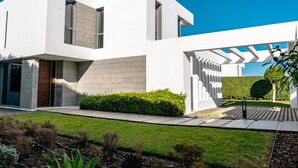 A modern two-story house with a white exterior, a wooden door, and a well-maintained garden. - Villa 'Dominica' with Sea View, Wi-Fi and Air Conditioning (Estepona)