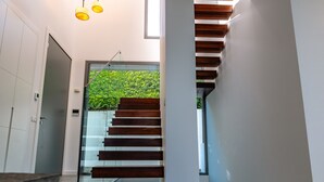 A modern staircase with glass railings and wooden steps, leading to a room with a view of greenery outside. - Villa 'Dominica' with Sea View, Wi-Fi and Air Conditioning (Estepona)