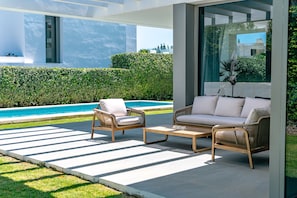 A modern outdoor seating area with wicker furniture and a pool in the background. - Villa 'Dominica' with Sea View, Wi-Fi and Air Conditioning (Estepona)